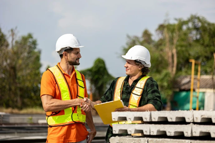 Two construction professionals shaking hands at a jobsite.